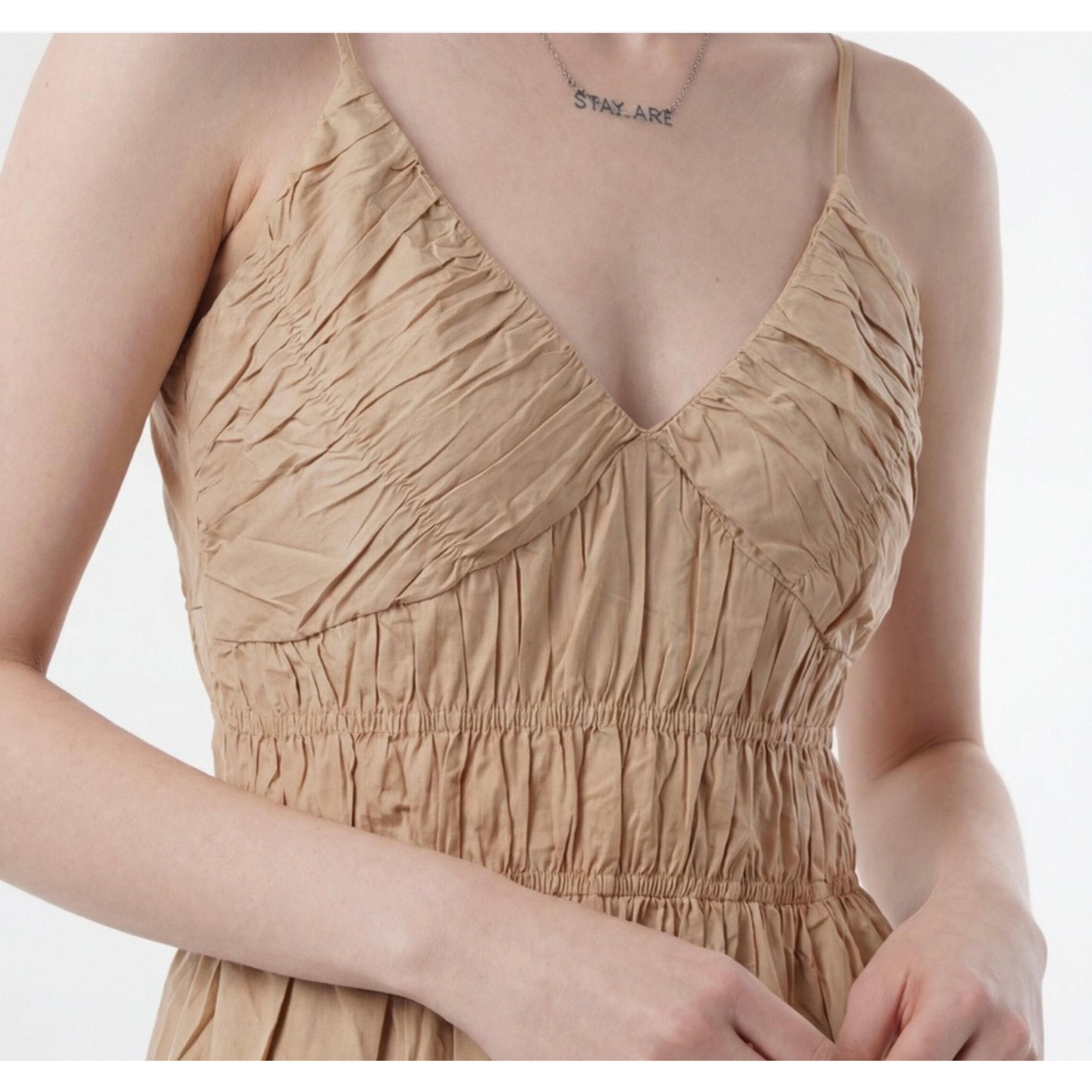 Beige sleeveless dress worn by a person on a white background