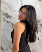 Woman in a black dress standing against a marble wall