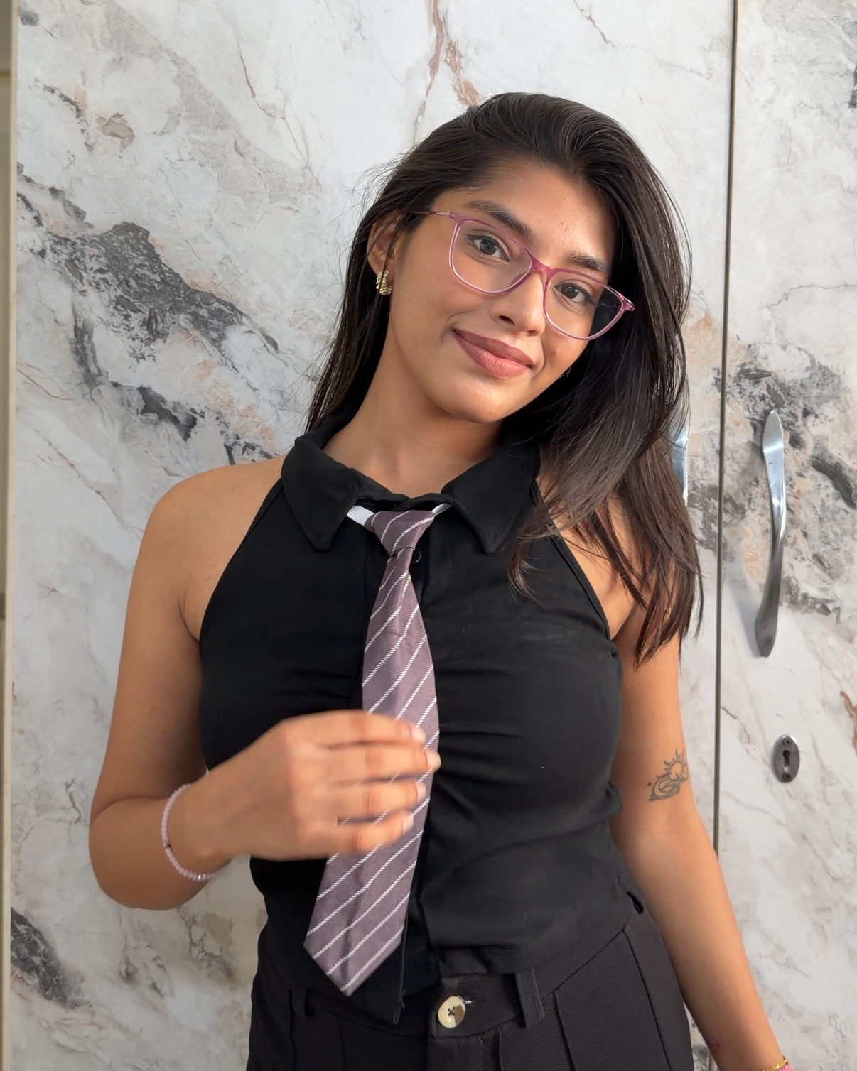 Woman holding a striped tie against a marble wall